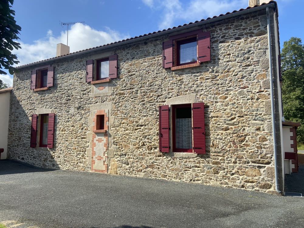 volets battants bordeaux sur maison en pierres